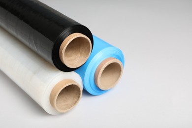Photo of Rolls of different stretch wrap on light grey background, closeup. Space for text