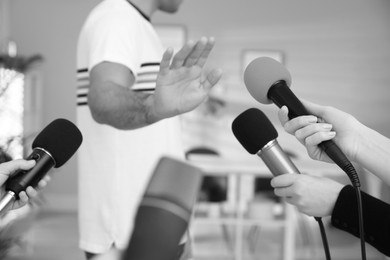 Image of Man avoiding journalist's questions at interview indoors, closeup. Black and white effect