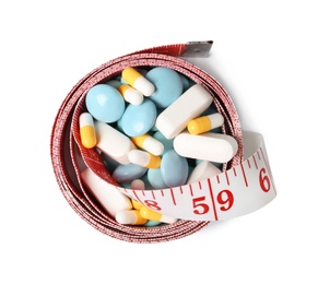 Photo of Weight loss pills and measuring tape on white background, top view