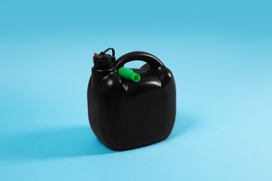 Photo of New black plastic canister on light blue background