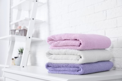 Stack of fresh towels on table in bathroom. Space for text