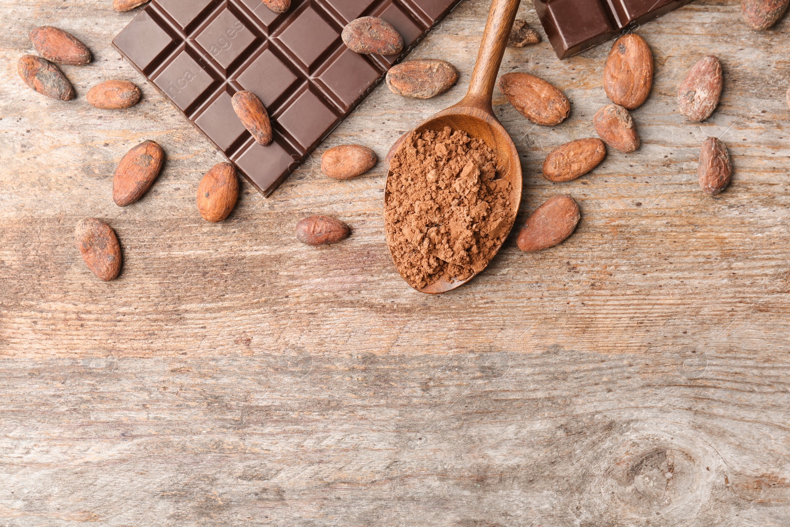 Photo of Flat lay composition with cocoa powder, beans and chocolate bar on wooden background