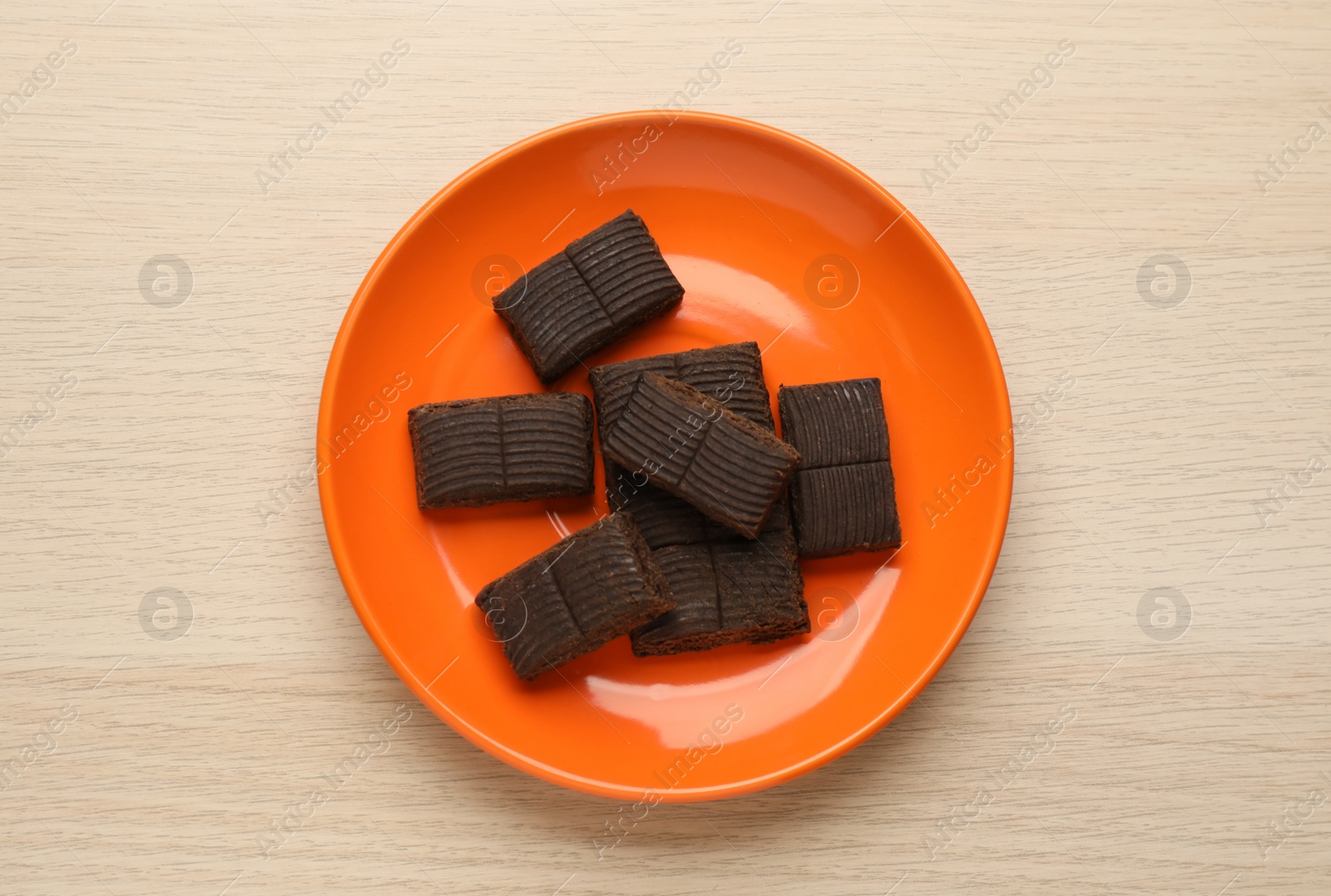 Photo of Orange plate with delicious and healthy hematogen on wooden table, top view