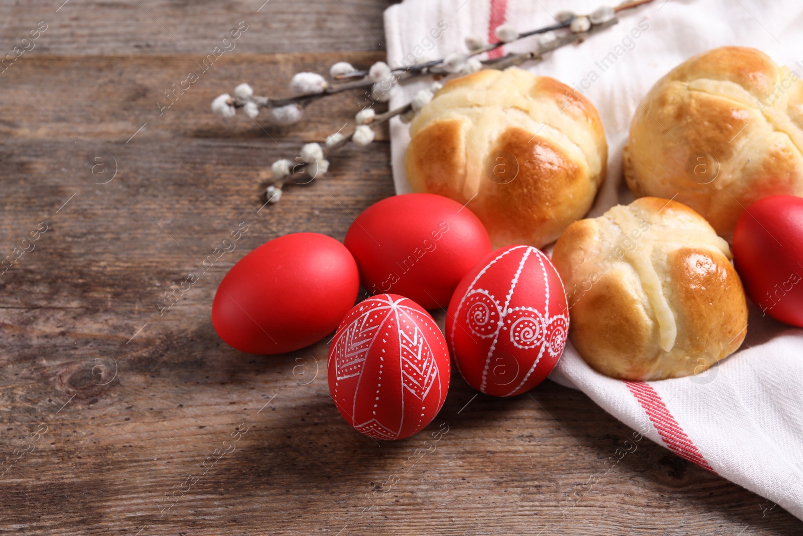 Photo of Red painted Easter eggs and buns on wooden table. Space for text