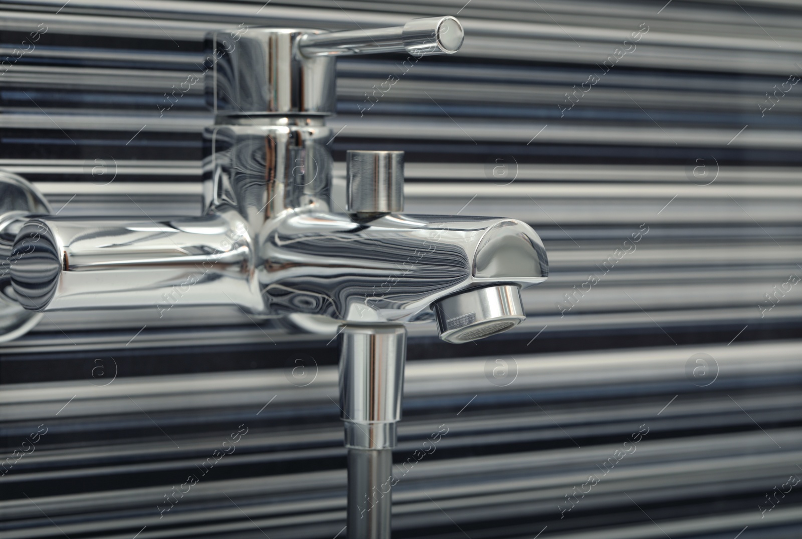 Photo of Shiny bath water tap installed on black and white wall