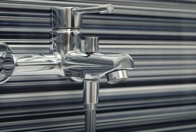 Photo of Shiny bath water tap installed on black and white wall