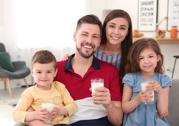 Photo of Happy family with glasses of milk in living room