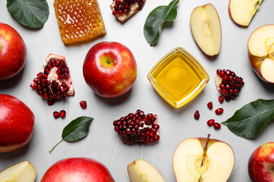 Honey, apples and pomegranates on light table, flat lay. Rosh Hashanah holiday