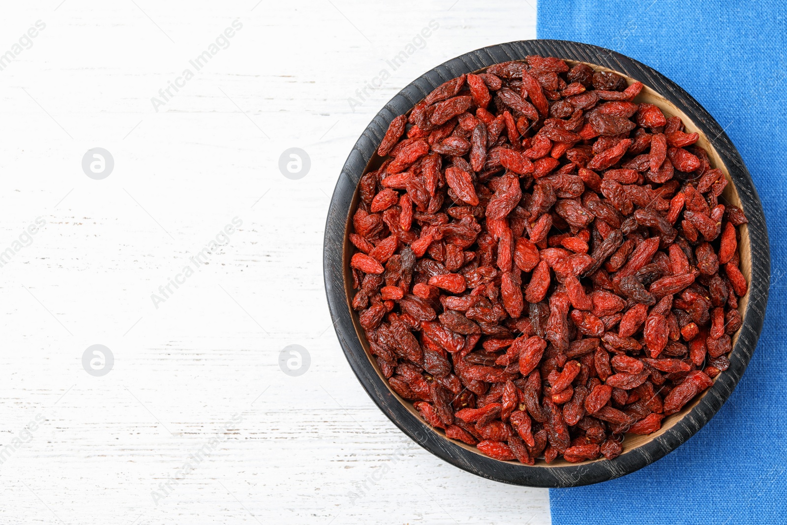 Photo of Dried goji berries on white wooden table, top view. Space for text