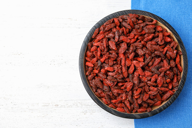 Photo of Dried goji berries on white wooden table, top view. Space for text