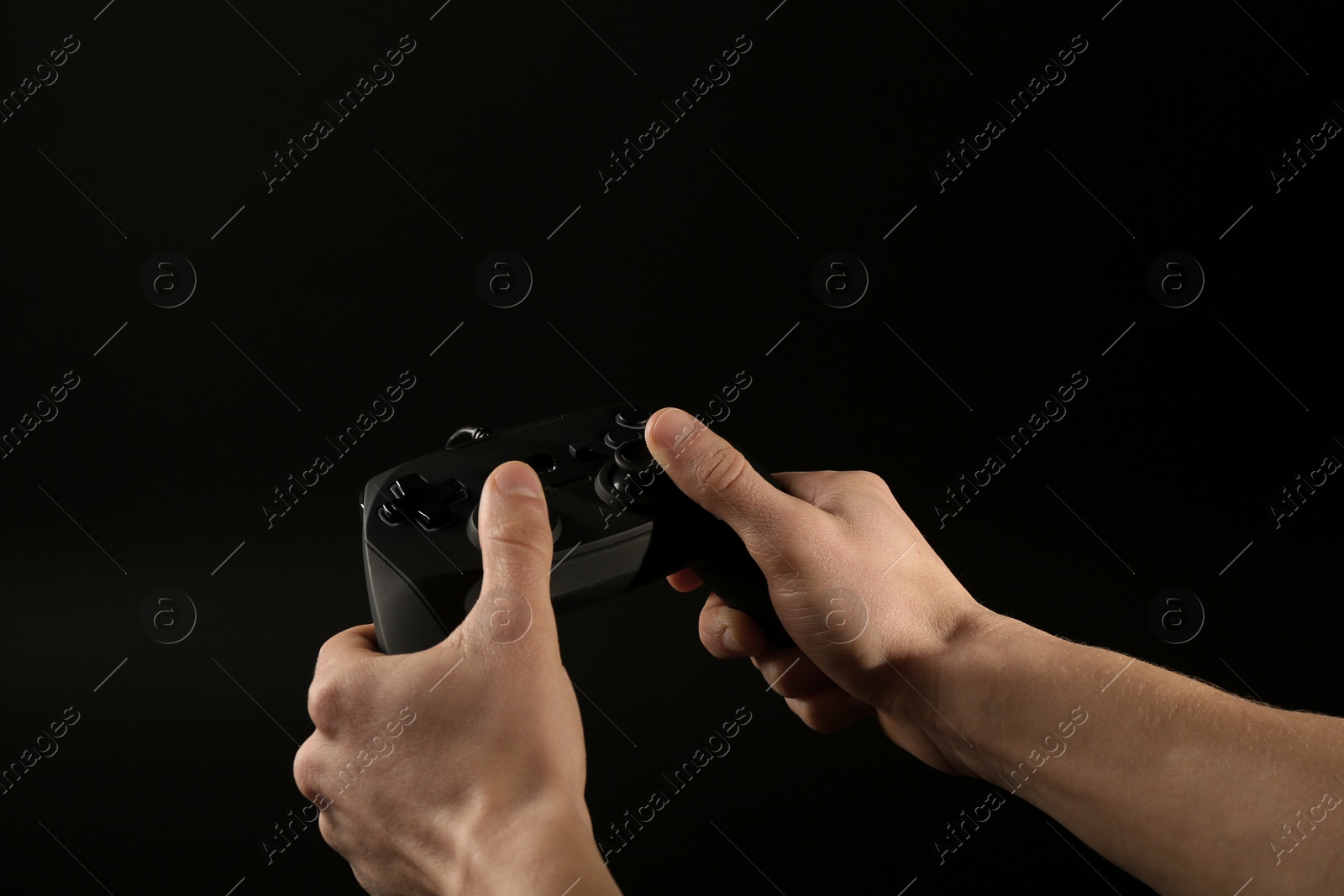 Photo of Man holding video game controller on black background, closeup