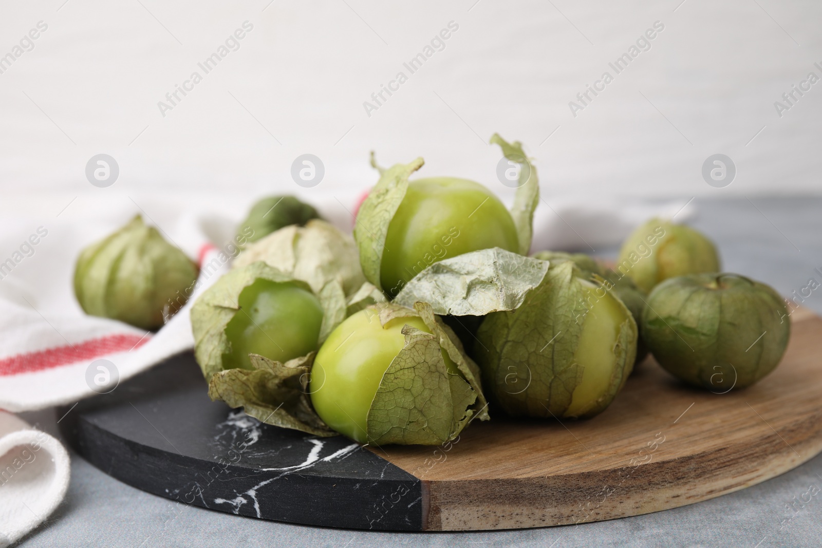 Photo of Fresh green tomatillos with husk on gray table, closeup