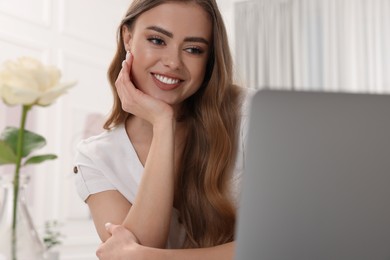Photo of Happy woman using laptop in living room