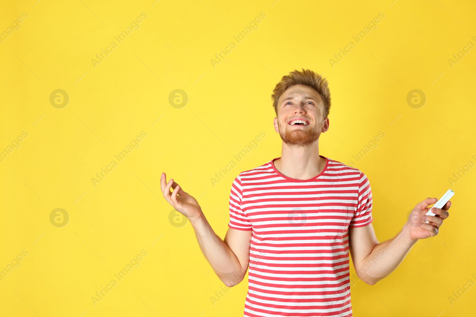 Photo of Young man with air conditioner remote on yellow background. Space for text