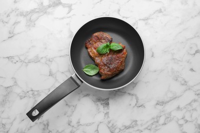 Tasty fried steak in pan on white marble table, top view