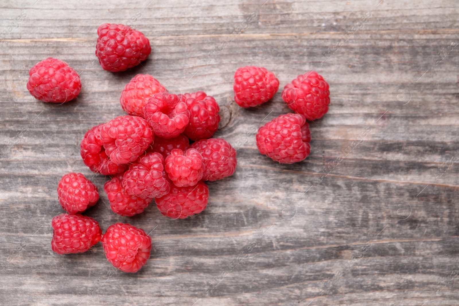 Photo of Tasty ripe raspberries on wooden table, top view. Space for text