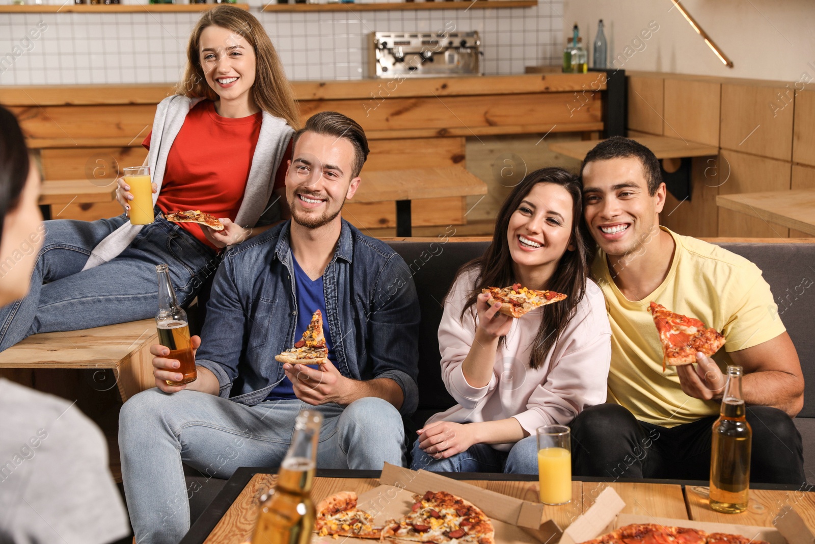 Photo of Group of friends having fun party with delicious pizza in cafe