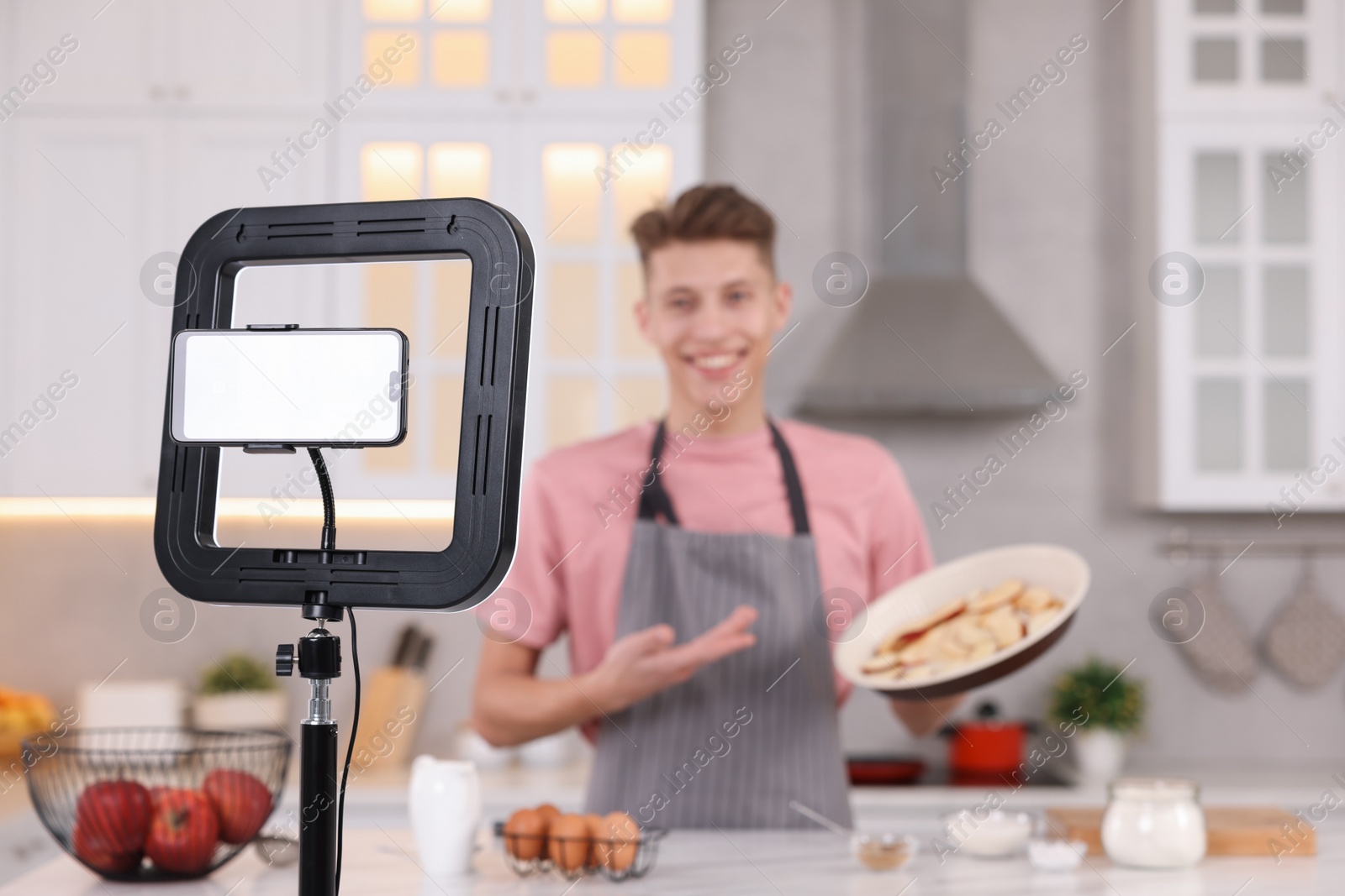 Photo of Food blogger recording video in kitchen, focus on smartphone