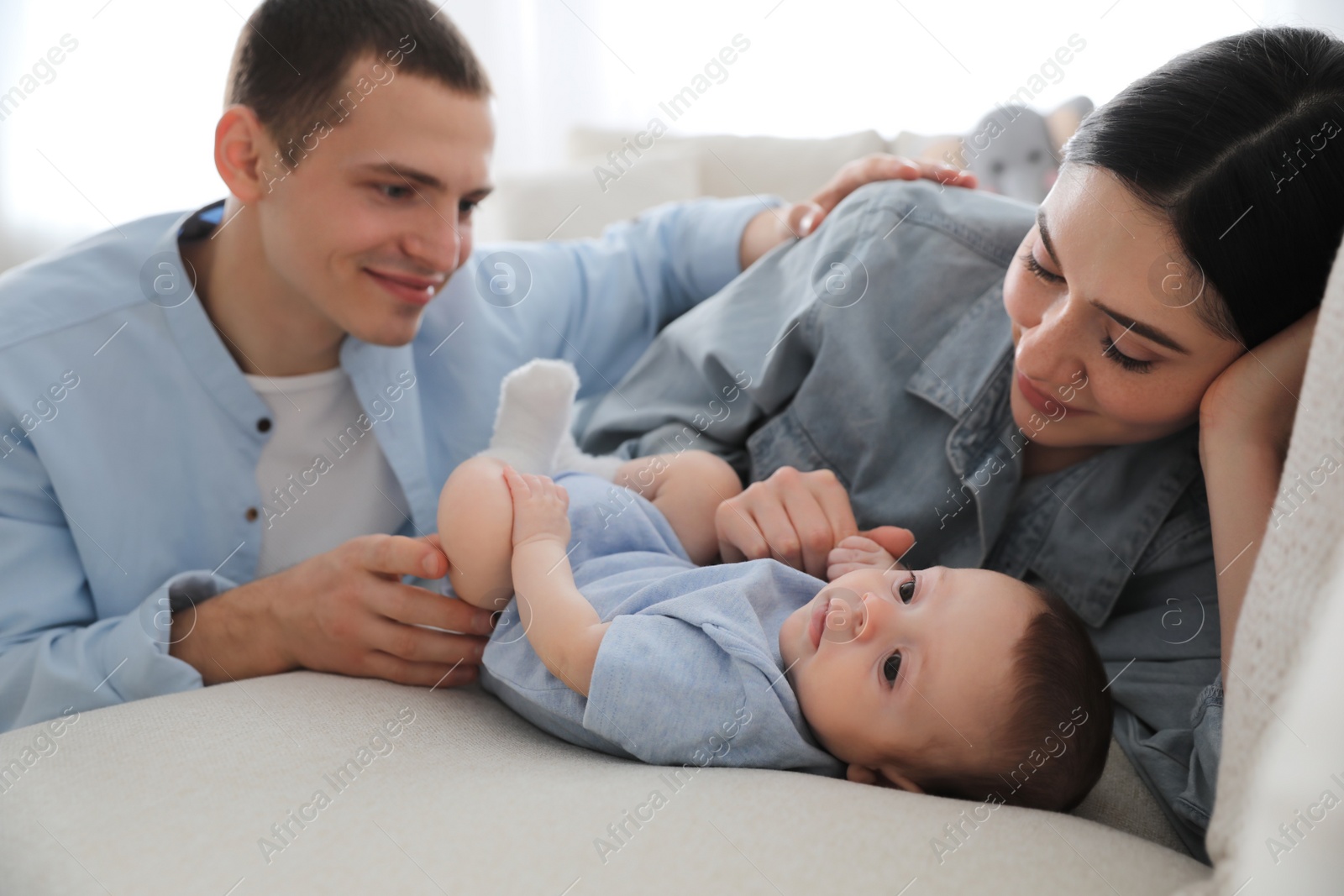 Photo of Happy family with cute baby on sofa at home