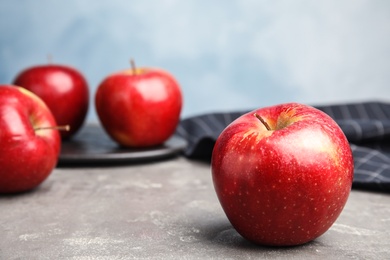 Ripe juicy red apple on grey table against blue background. Space for text