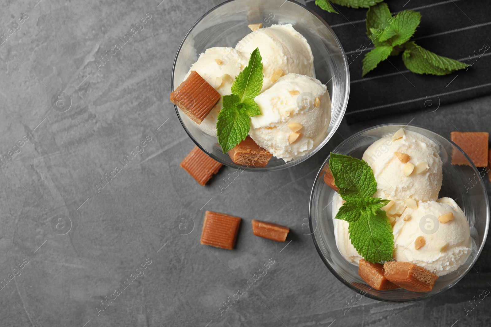 Photo of Flat lay composition of ice cream with caramel candies and space for text on grey table