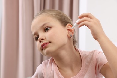 Photo of Little girl using ear drops at home