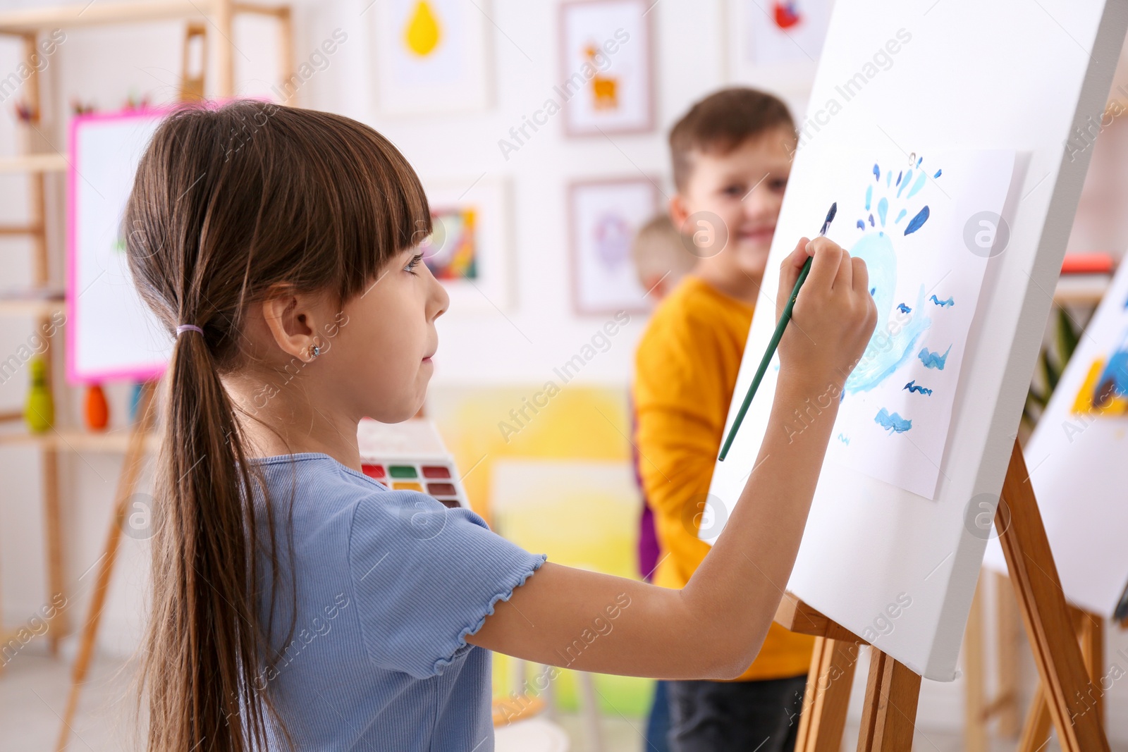 Photo of Cute little child painting during lesson in room