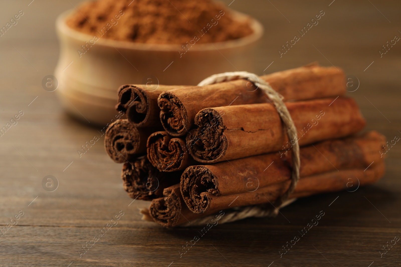 Photo of Dry aromatic cinnamon sticks on wooden table, closeup