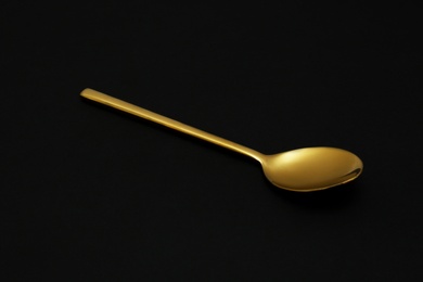 Shiny luxury gold spoon on black background