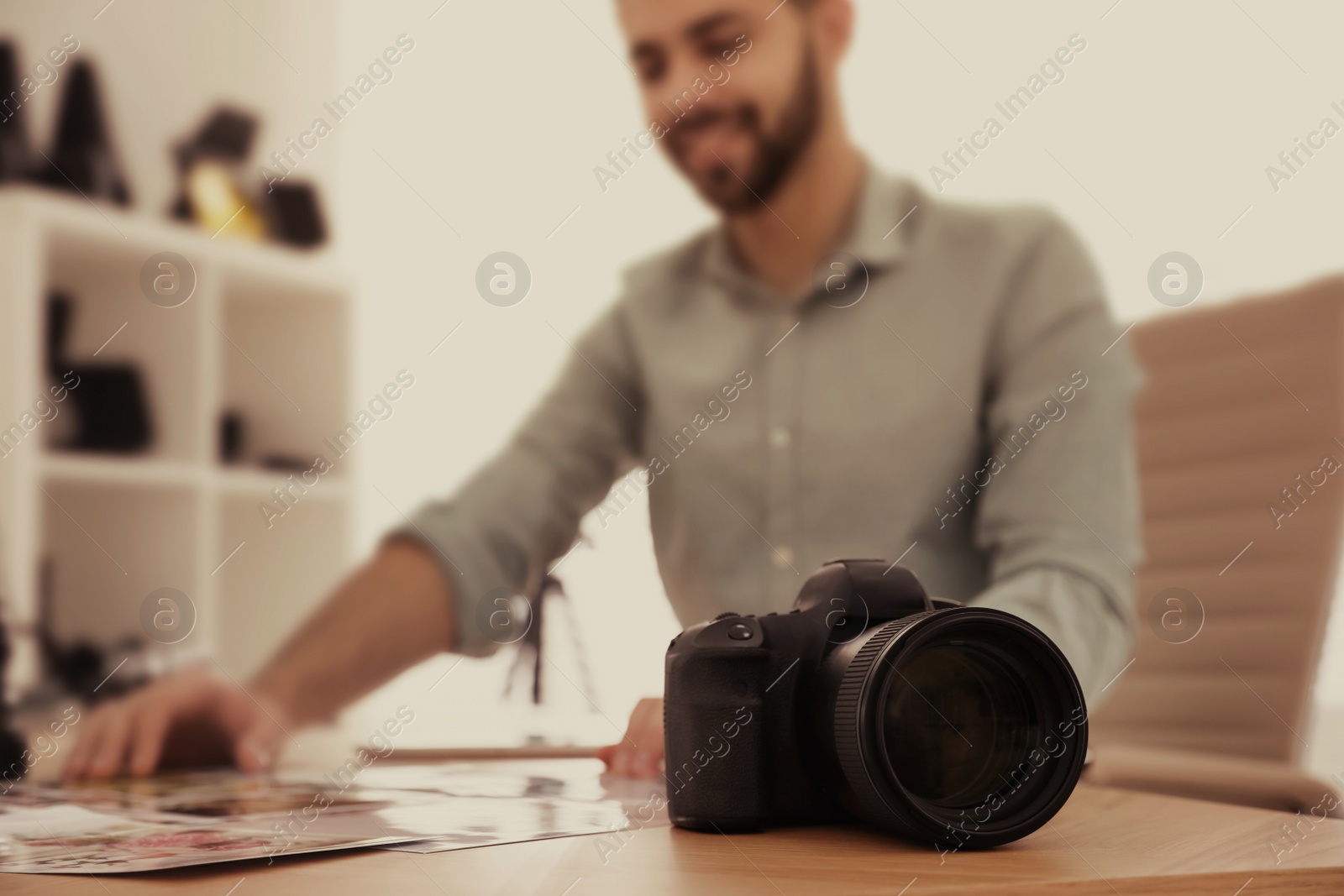 Image of Professional photographer working at table in office, focus on camera