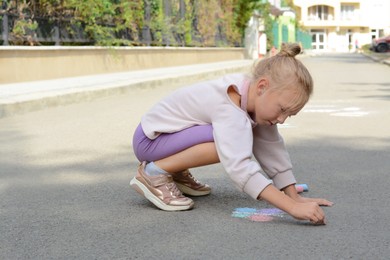 Little child drawing butterfly with chalk on asphalt