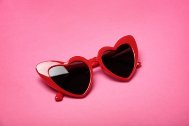 Photo of Stylish heart shaped glasses on color background