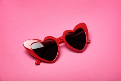 Stylish heart shaped glasses on color background