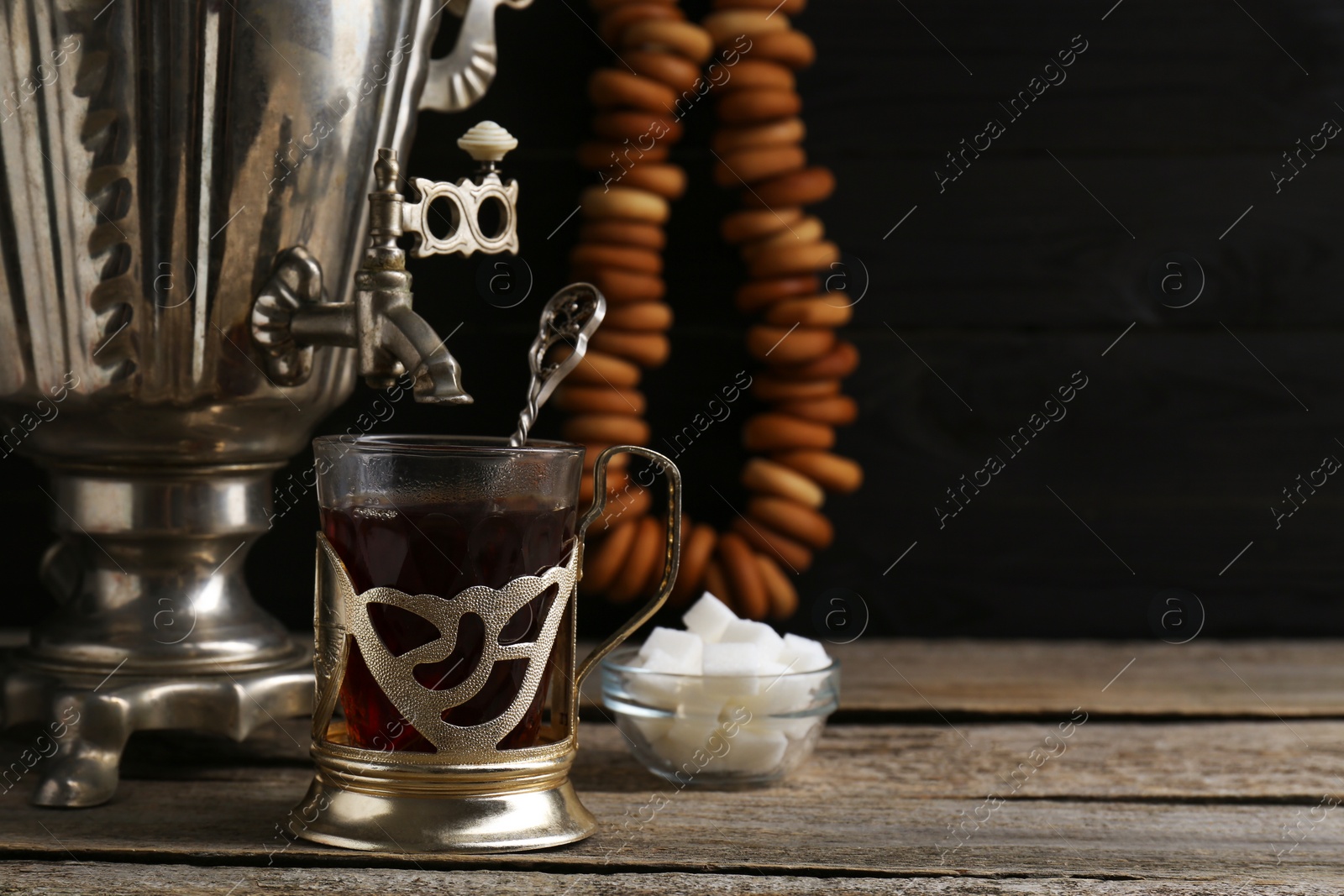 Photo of Delicious tea and ring shaped Sushki (dry bagels), focus on cup with samovar. Space for text
