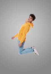 Teenage boy jumping on grey background, full length portrait