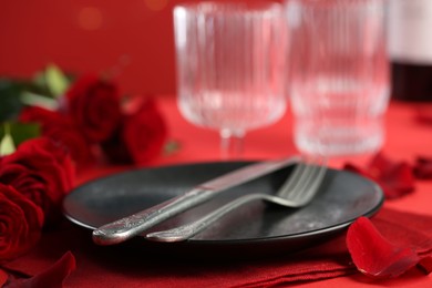 Photo of Place setting with roses on red table, closeup. Romantic dinner