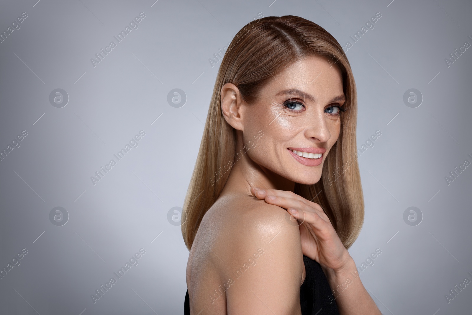 Image of Portrait of stylish attractive woman with blonde hair smiling on grey background, space for text