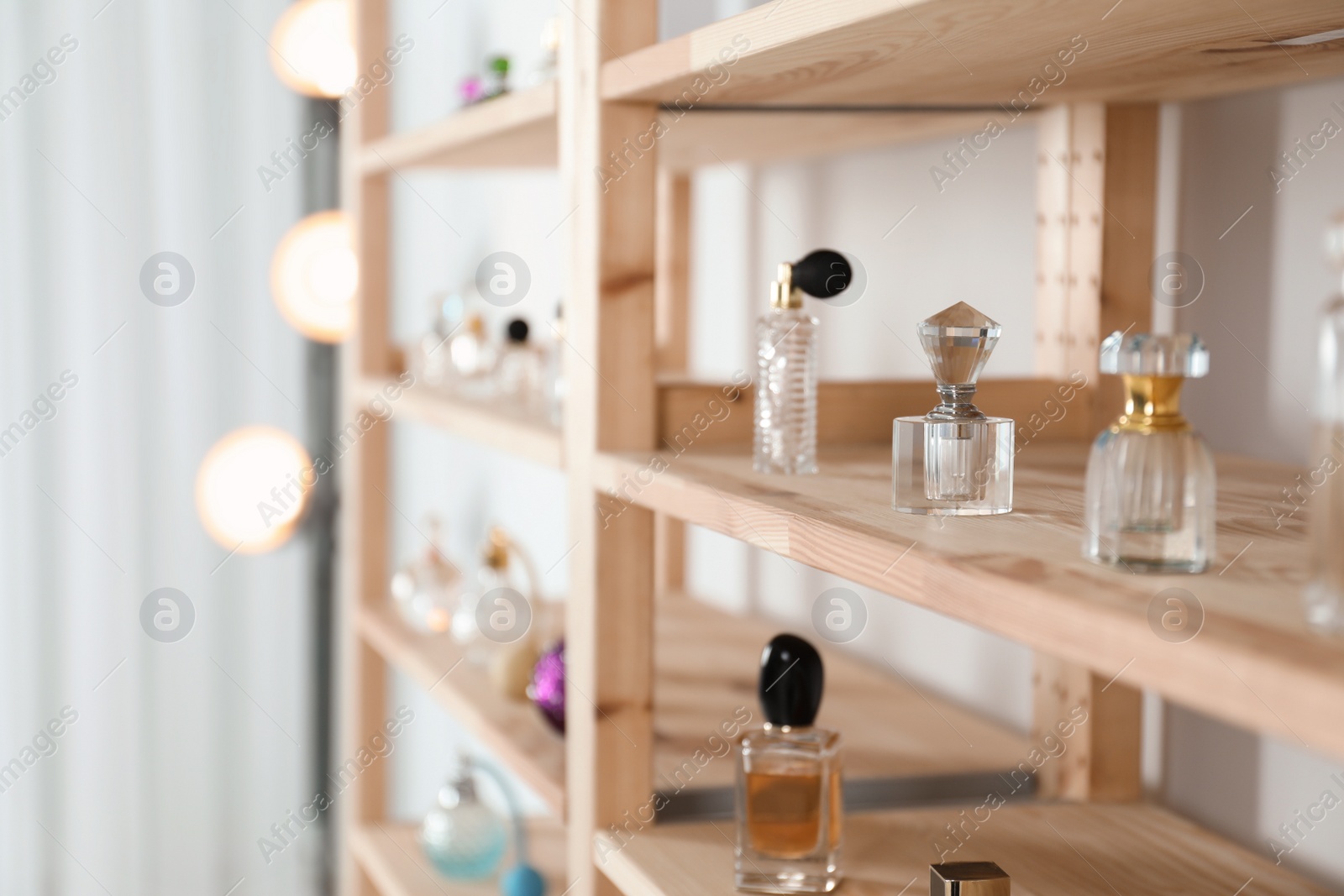 Photo of Different perfume bottles on wooden rack indoors