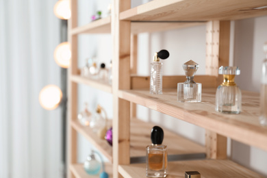 Photo of Different perfume bottles on wooden rack indoors