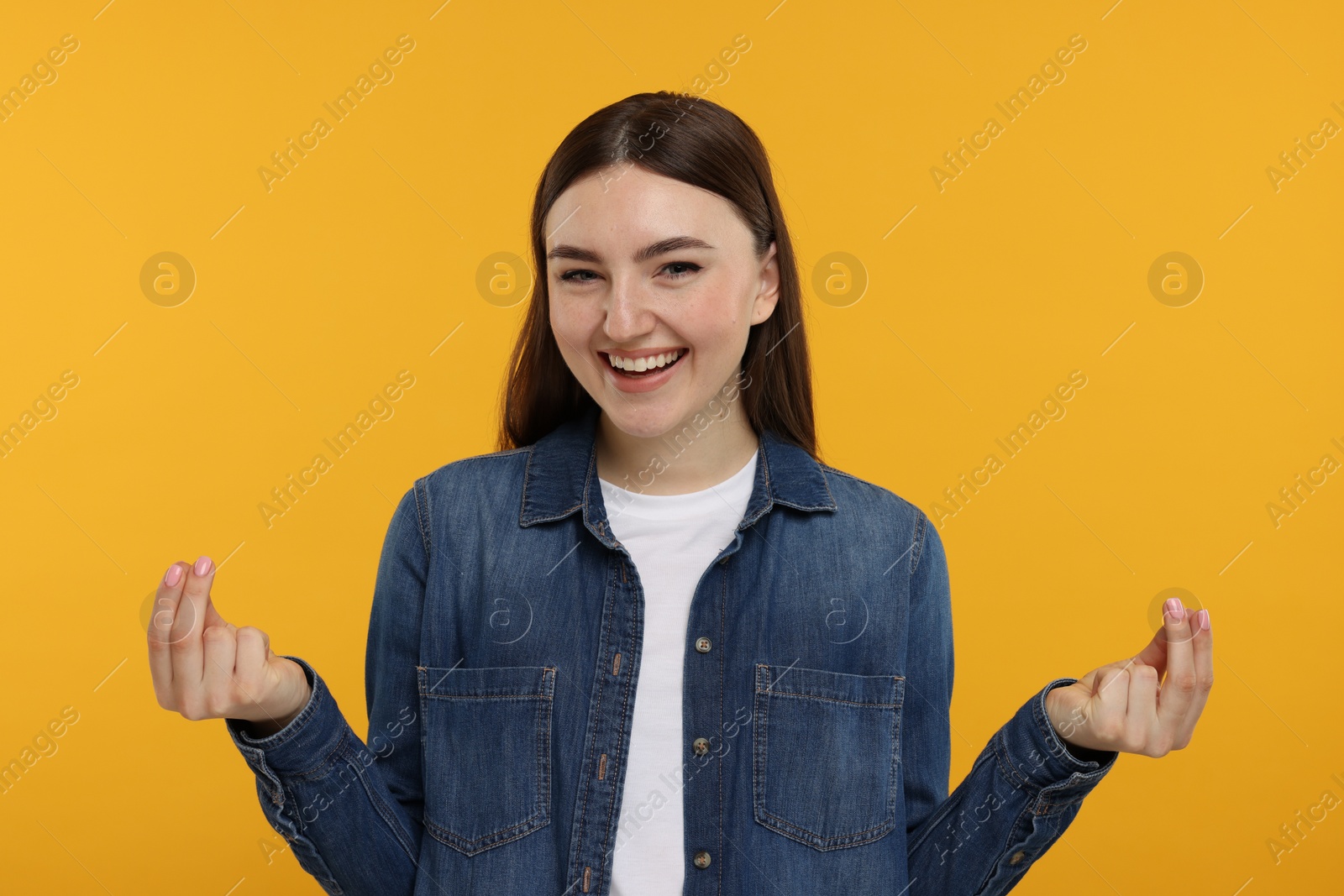 Photo of Happy woman showing money gesture on orange background