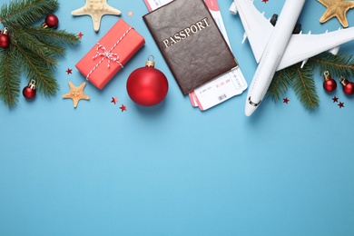 Flat lay composition with Christmas decorations, passport and airline tickets on blue background, space for text. Winter vacation