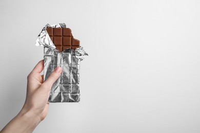 Photo of Woman holding delicious chocolate bar on white background, closeup. Space for text