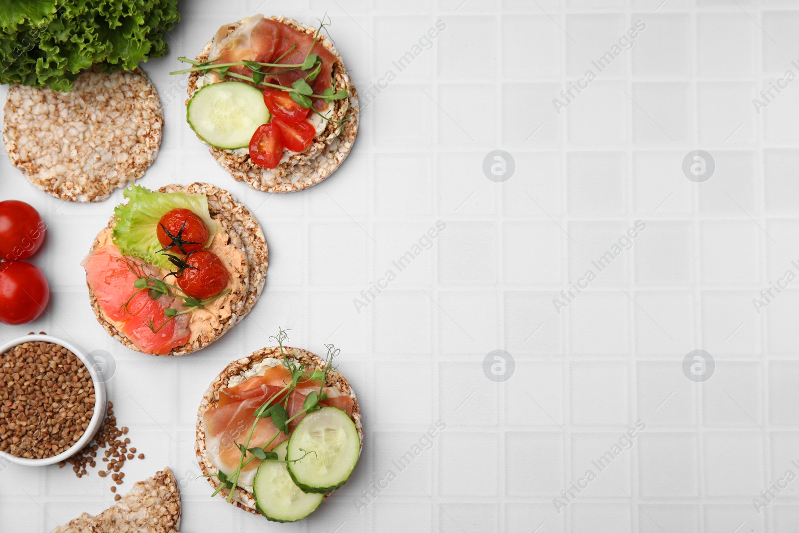 Photo of Set of crunchy buckwheat cakes with different ingredients on white background, flat lay. Space for text