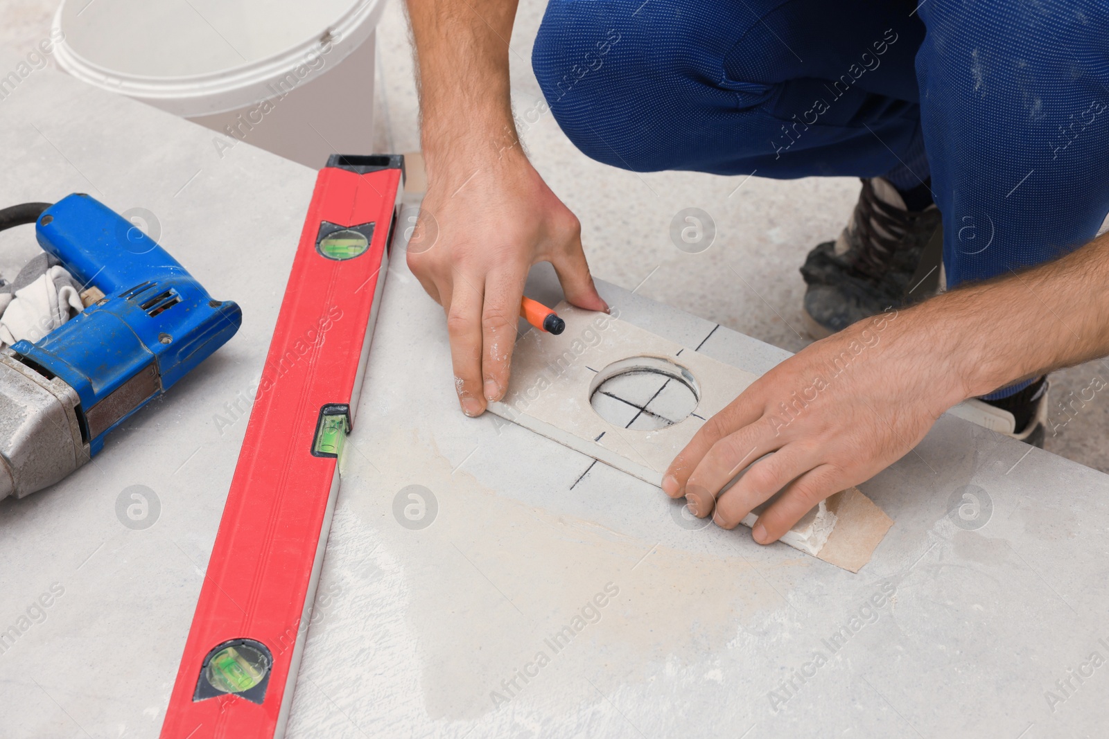 Photo of Worker making socket hole in tile indoors, closeup