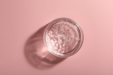 Jar of cosmetic gel on pink background, top view