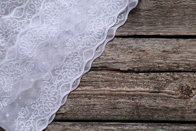 Photo of White lace on wooden table, top view. Space for text