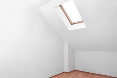 Skylight roof window and lamps on slanted ceiling in attic room