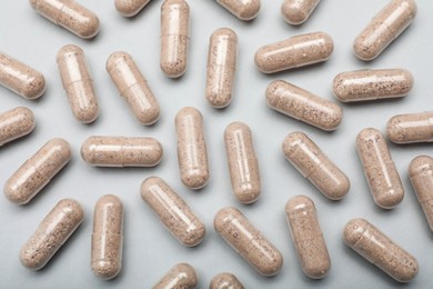 Many gelatin capsules on light grey background, flat lay