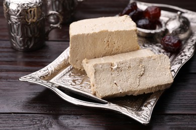 Photo of Pieces of tasty halva served on vintage tray on wooden table, closeup