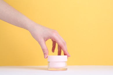 Photo of Woman with jar of cream on yellow background, closeup